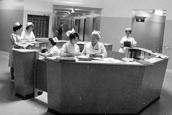 Some nurses working in a station at a 1960 setting