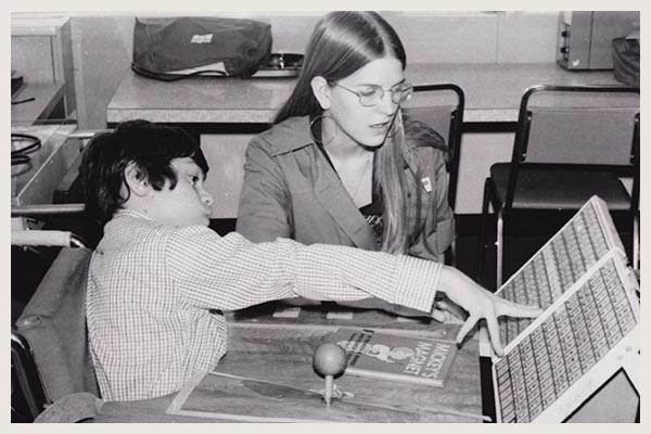 Black and white photo of an adult and a children using an old book