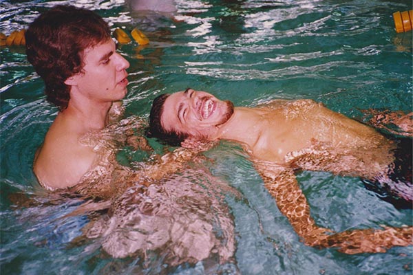 An adult swimming coach teaching another adult how to swim