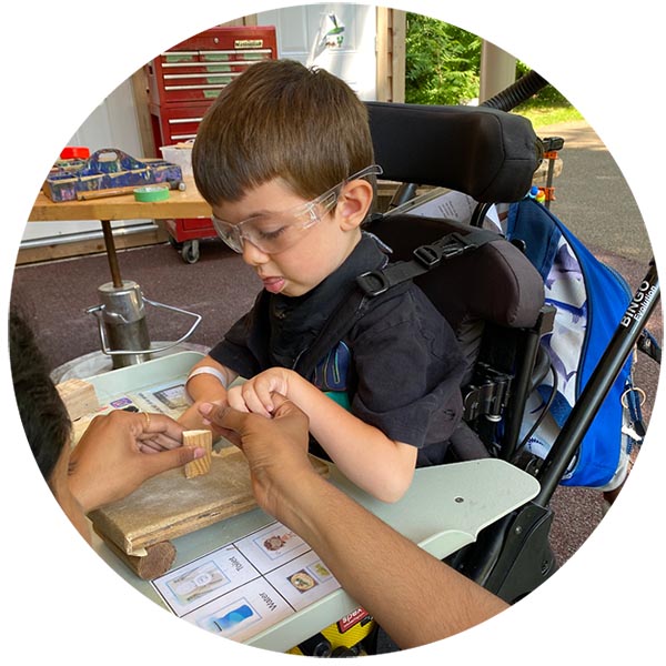 A child sitting on wheelchair to touch a piece of wood