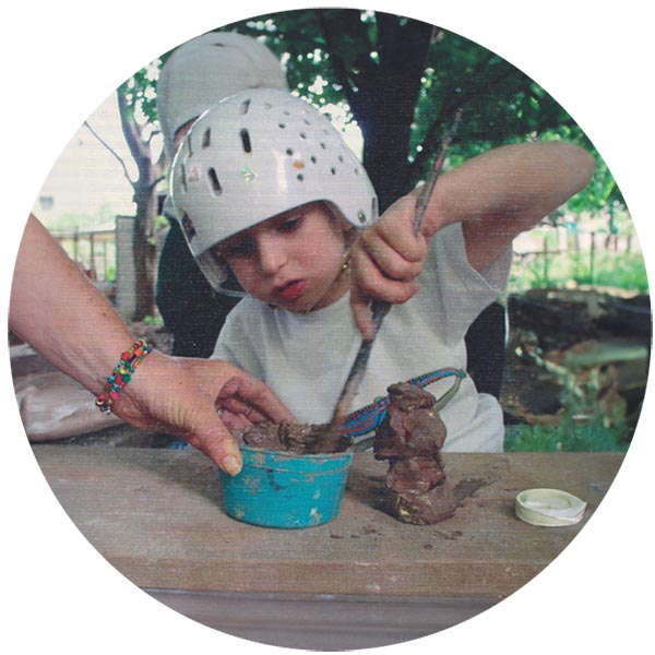 A child with helmet on mixing soil and clay to prepare to plant