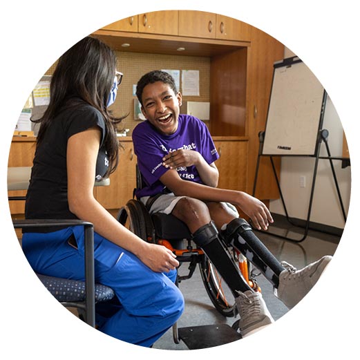 An adult is talking with a child who is on a wheelchair